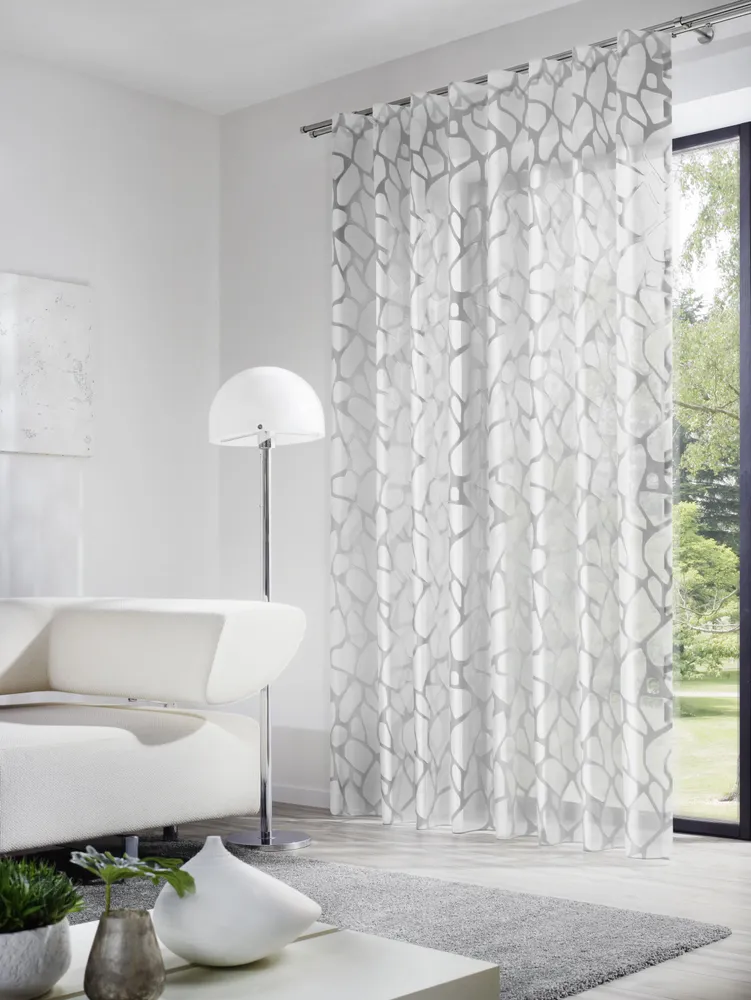 INKU Dekostoff STOR Deluxe Transparence – luftige Eleganz mit floralem Muster INKU Vorhang STOR Deluxe Transparence mit transparentem floralen Muster vor bodentiefem Fenster