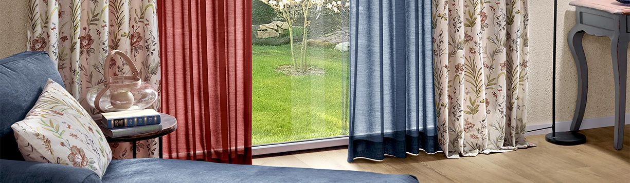 Verschiedene Dekostoffe und Stores als Vorhänge in kräftigen Farben vor einer Terrassentür