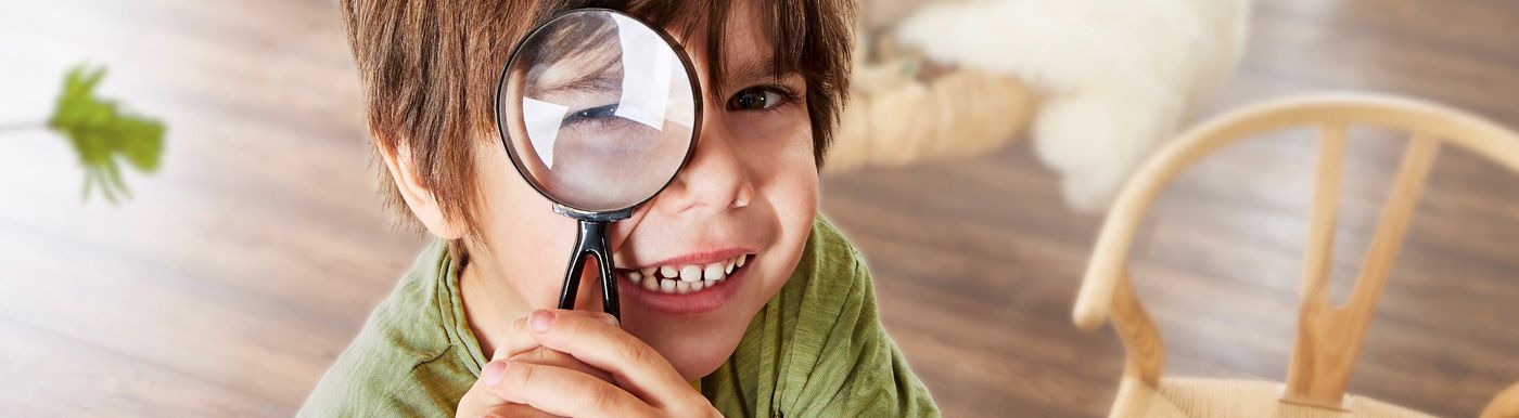 Kind mit Lupe auf INKU Xplora Naturdesignboden – Fokus auf spielerisches Entdecken und umweltbewusstes Wohnen