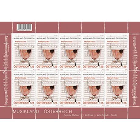 A large Viennese timpani (a classical percussion instrument), depicted in realistic form. The kettle is copper-colored, the drumhead surface is white, and the mechanism underneath is clearly visible. In the background, a sheet of music with musical notes and staff lines