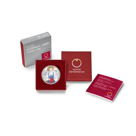 Packshot_10E-Aufdrindln-Leinen_WEB Austrian 10 Euro silver coin 'Aufdirndln - Linen' in a red Münze Österreich box with certificate of authenticity.