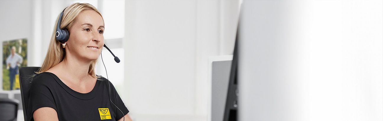 Austrian Post employee with headset at a customer service desk, wearing a black shirt with the Post logo.